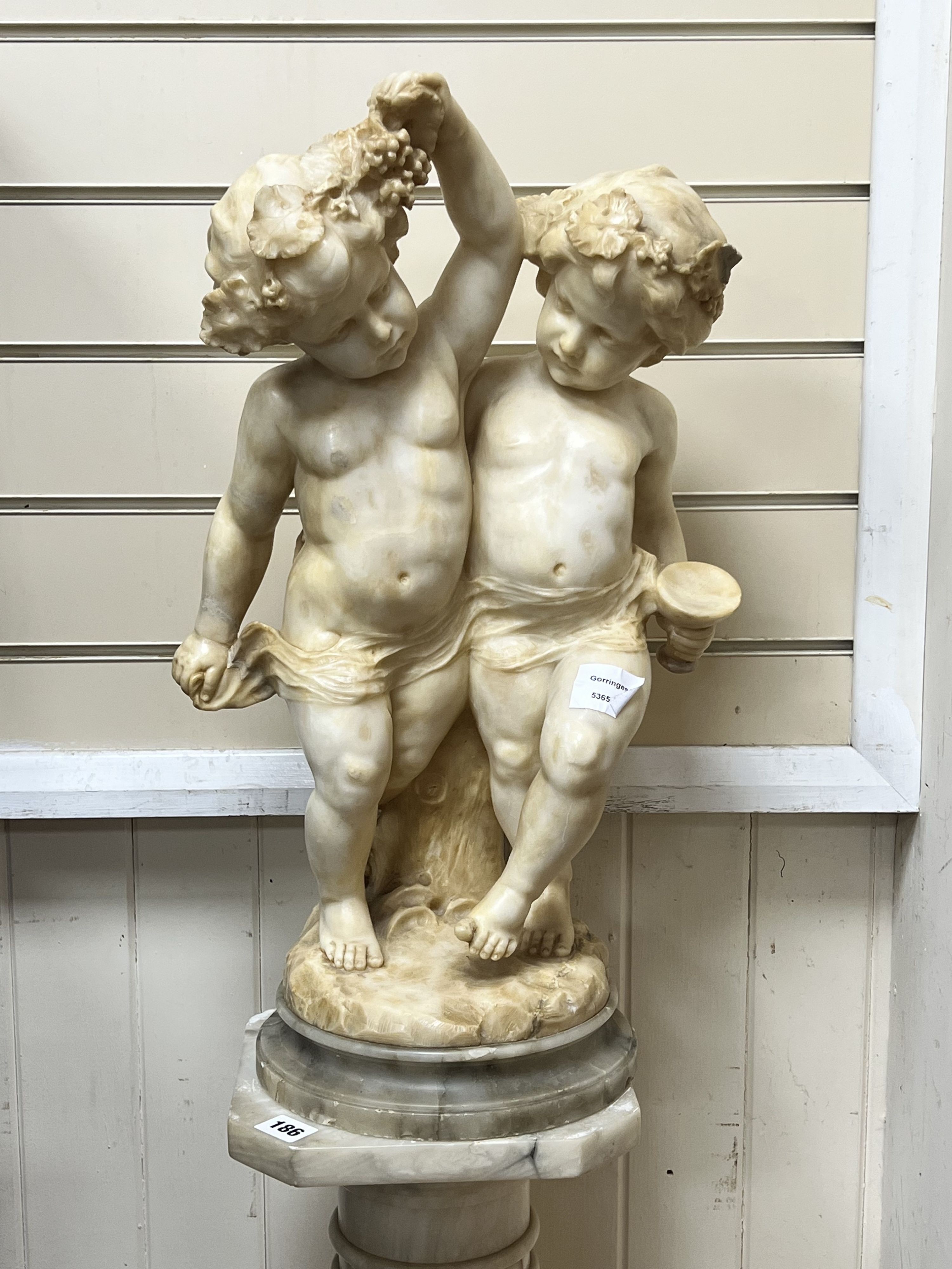 An Italian alabaster carving of bacchic cherubs on fluted pedestal, overall height 130cm
